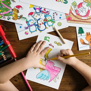 Child's hands colouring in picture on desk with pencils