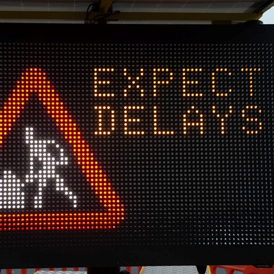 Illuminated warning sign showing men at work