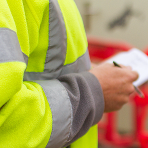 A person in hi-vis with notebook illustrating covid safety checks for businesses