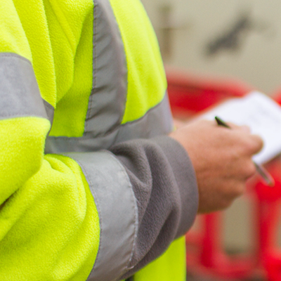 A person in hi-vis with notebook illustrating covid safety checks for businesses