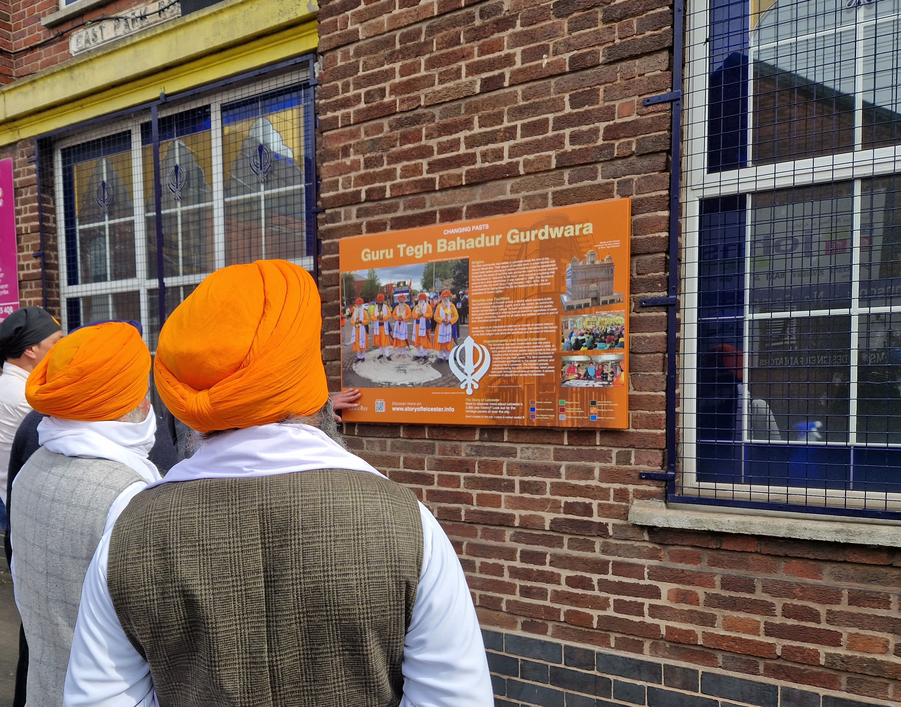 Members of Guru Tegh Bahadur Gurdwara looking at new panel