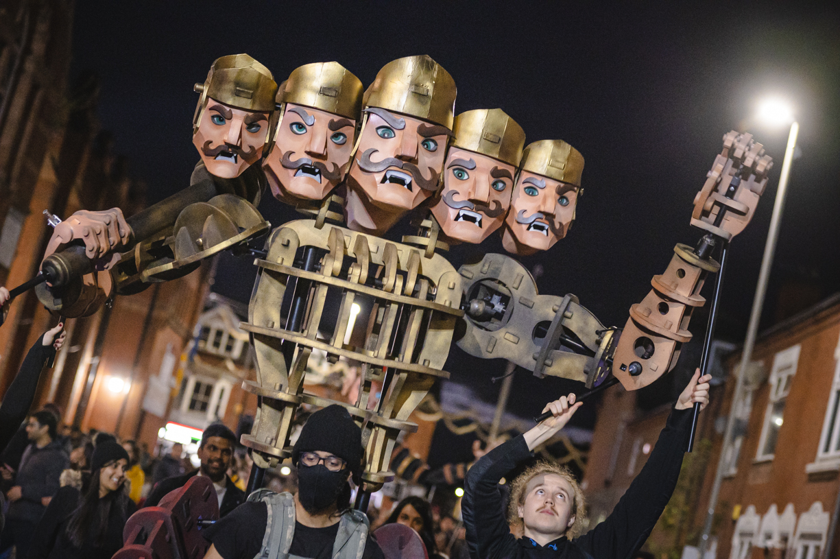 A giant five-headed warrior puppet against a dark night sky.