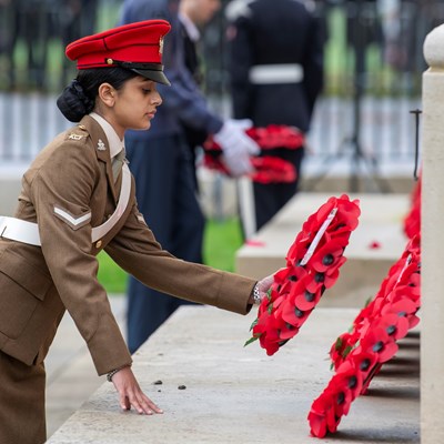 Woman in military uniform laying a poppy wreath at the War Memorial