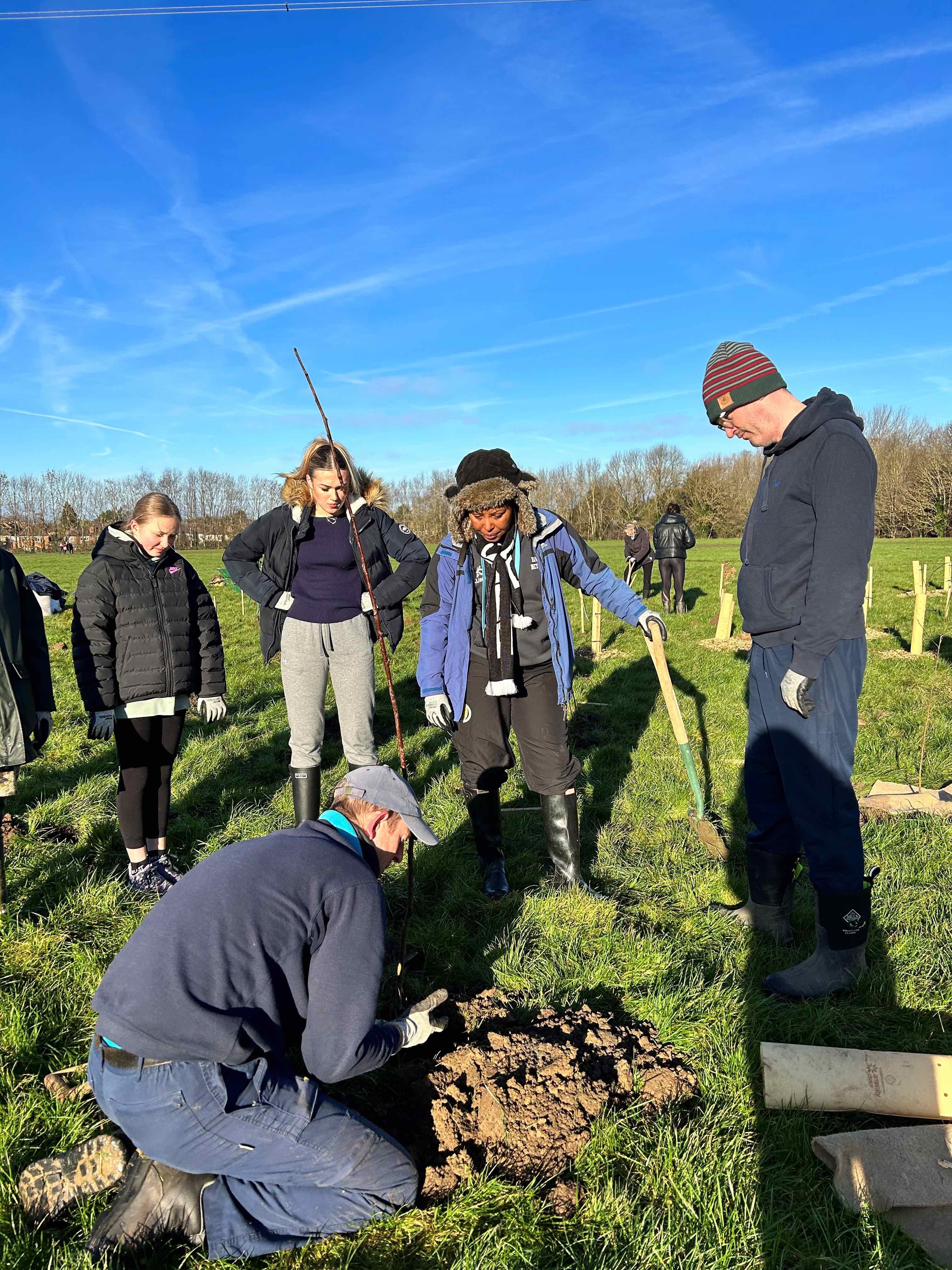Members of the netball team get some tips on tree planting from council staff