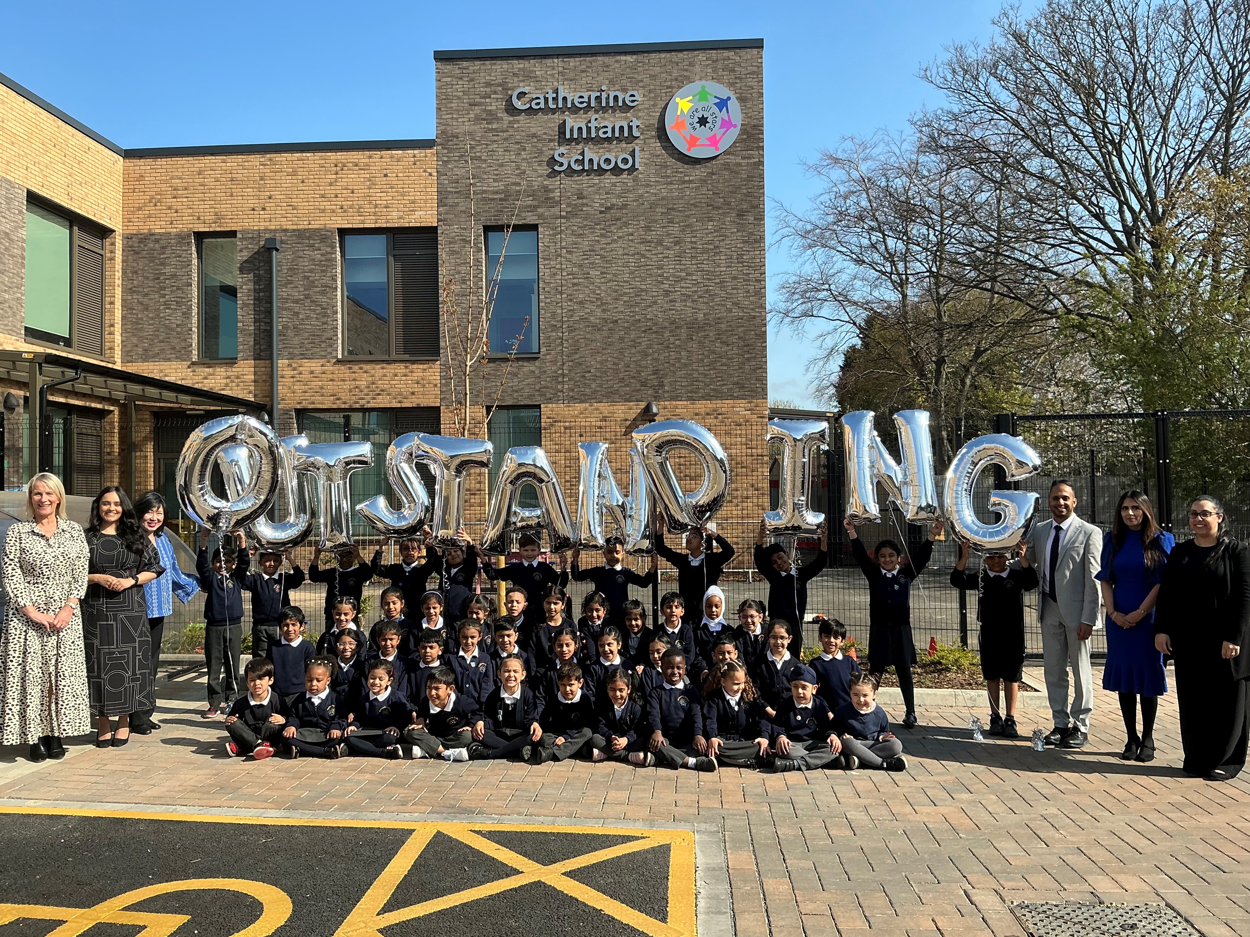 Pupils and staff holding up balloons to celebrate their outstanding Ofsted at Catherine Infant School