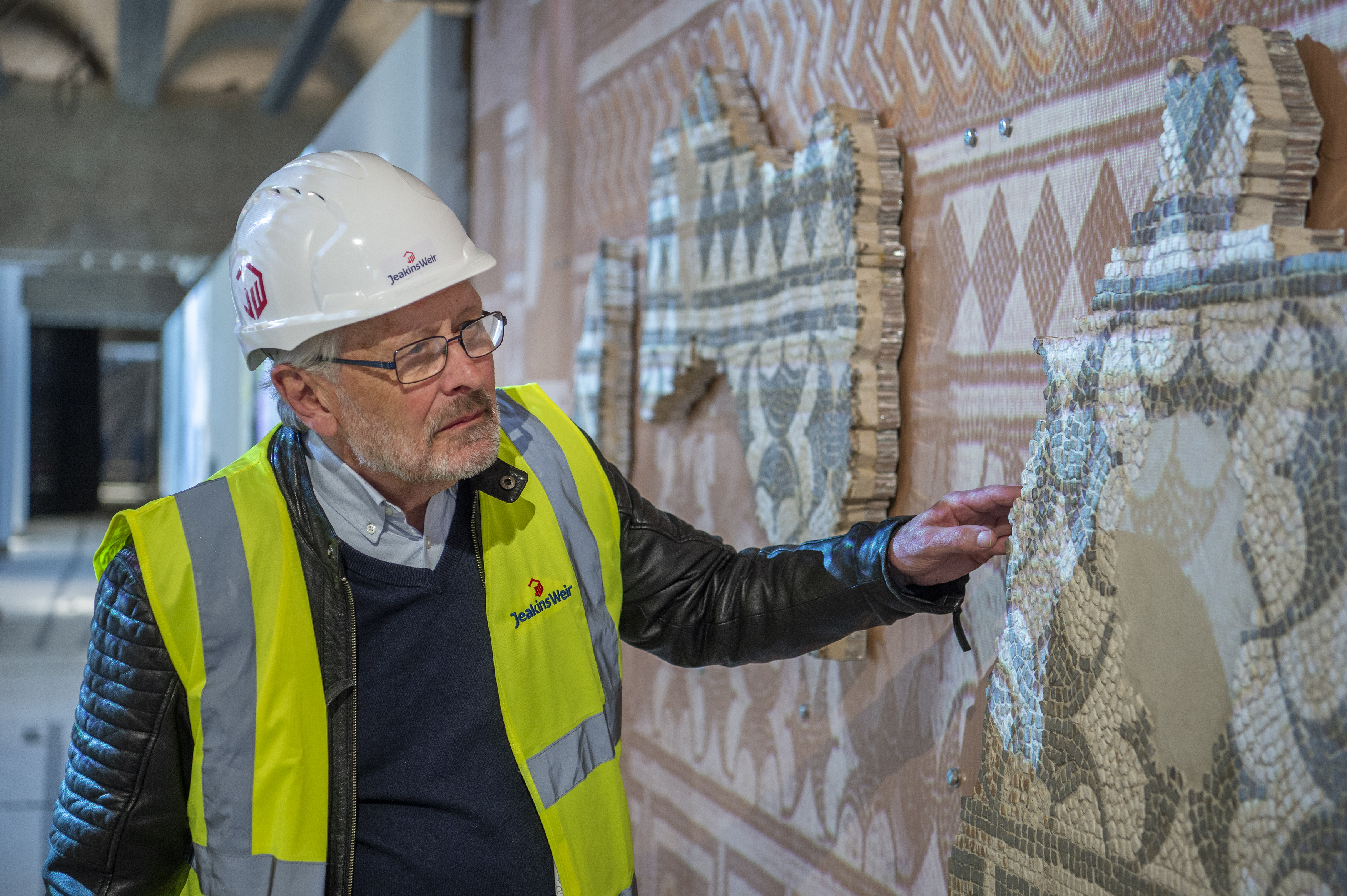 The city mayor in hard hat inspects a mosaic on the wall