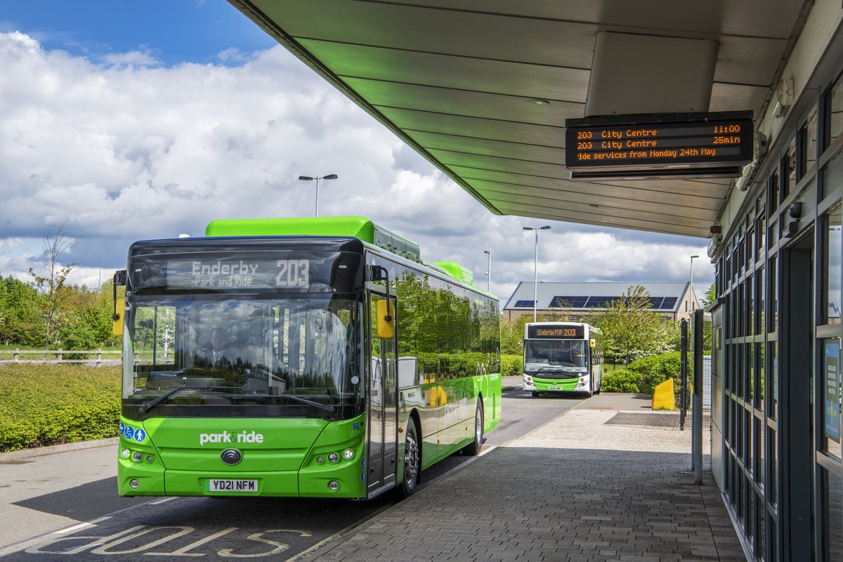A green park and ride bus parked next to the terminal