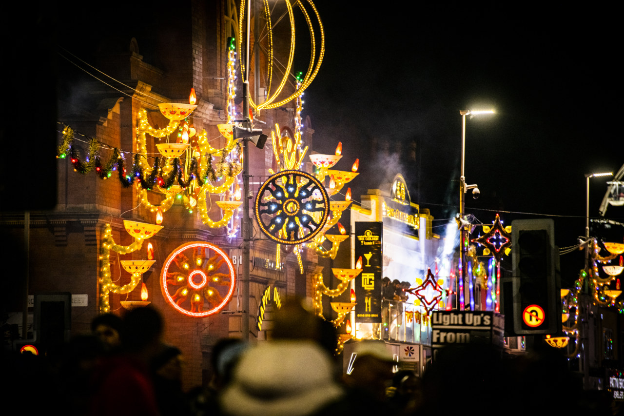 Colourful Diwali lights on street buildings against a dark sky