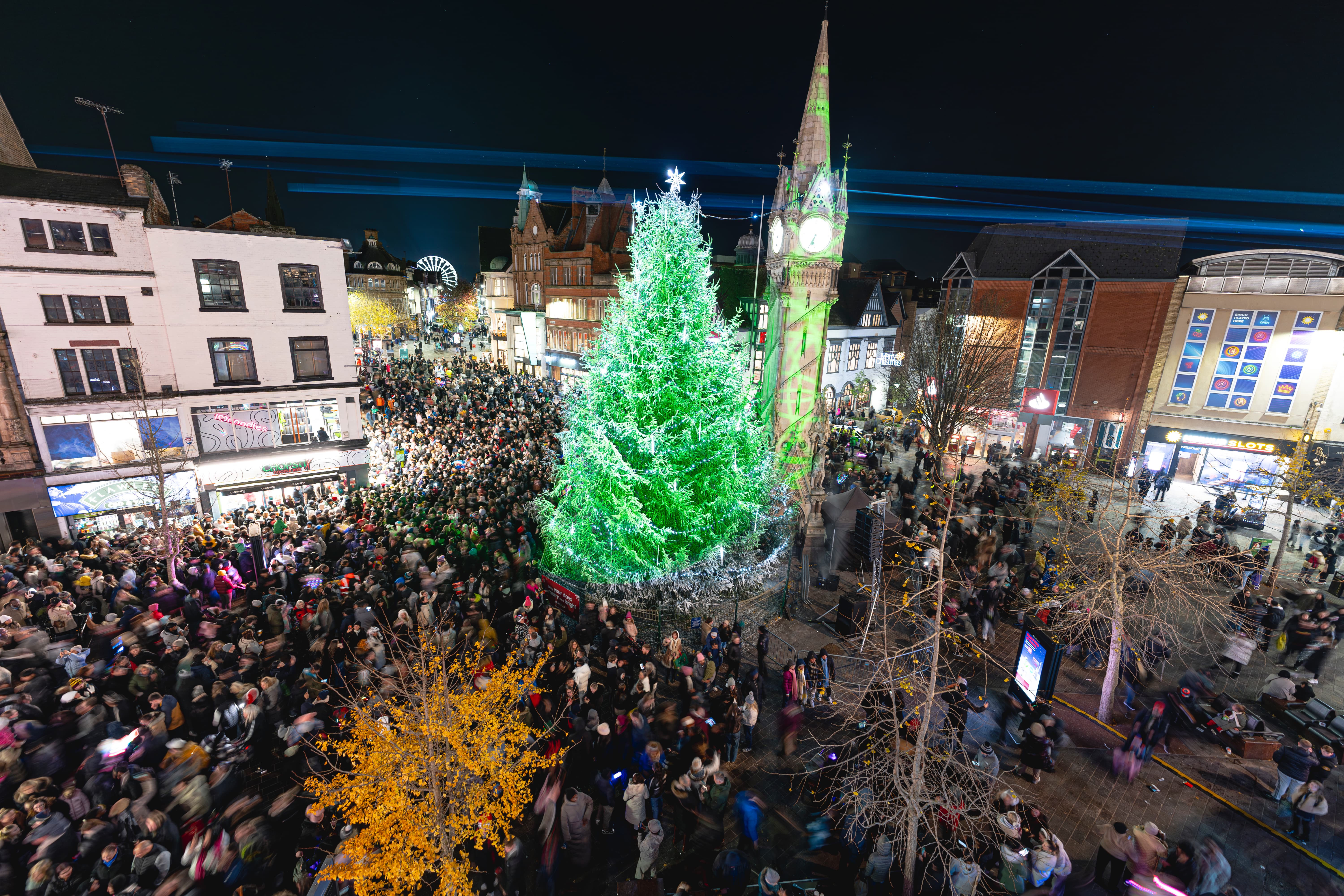BUSINESSES in Leicester are being asked to help to fill the city with Christmas cheer by sponsoring Christmas trees that will light up public spaces or their own premises, throughout the festive season. 50 foot Christmas tree stands next to Leicester Clock Tower surrounded by huge crowds of people.