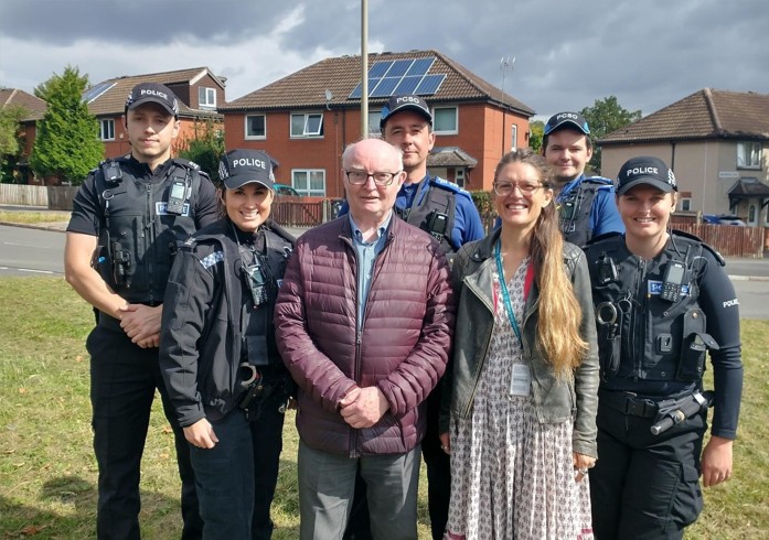 Five police officers in uniform and two councillors stand together on the Saffron Lane estate